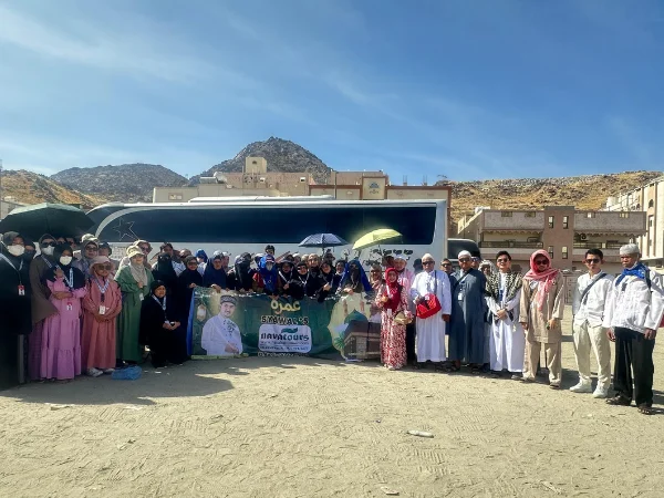 Peserta umroh syawal berfoto bersama rombongan di depan bus ziarah